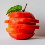 Artistic stack of sliced apple pieces with a fresh green leaf.